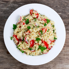 Homemade Fresh Couscous salad with vegetables, in white plate.