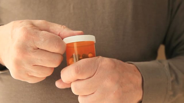 Front view of senior man trying to open a child-proof pill bottle