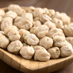 Rohe Kichererbsen (lat. Cicer arietinum) auf kleinem Holzteller, fotografiert mit natürlichem Licht (Selektiver Fokus, Fokus ein Drittel in das Bild)