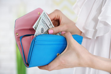 Young woman getting dollars banknotes from purse