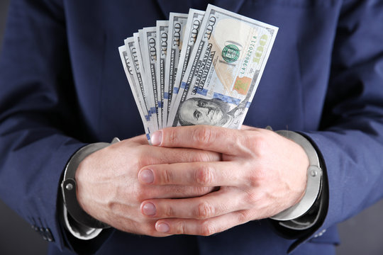 Man in handcuffs counting dollar banknotes, close up