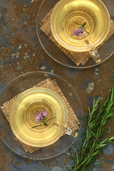 Frischer Rosmarin Kräutertee in Glastassen garniert mit Rosmarinblüten, fotografiert mit natürlichem Licht (Selektiver Fokus, Fokus auf die Blüten)