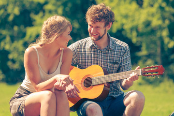 Young couple camping playing guitar outdoor