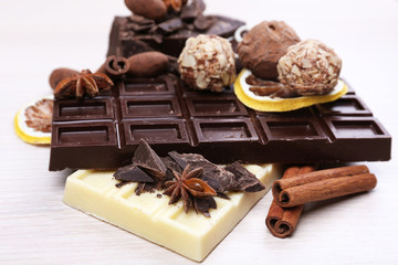 Pieces of chocolate with lemon and cinnamon sticks on wooden background