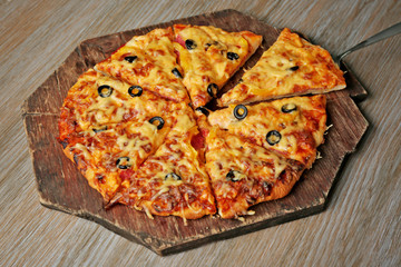 Delicious sliced pizza on wooden board, close up