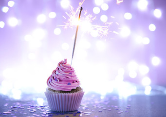 Cupcake with pink cream icing and sparkle on a glitter background
