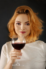 Young woman with glass of red wine on blurred background