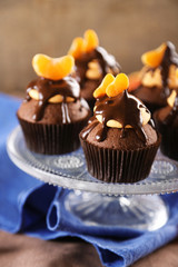 Tasty cupcakes with slice of mandarin and chocolate on wooden background