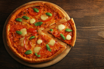 Sliced Margherita pizza on wooden background