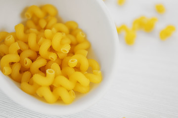 Fresh uncooked pasta in bowl on wooden table closeup