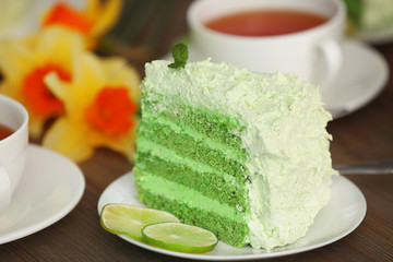 Piece of delicious creamy lime cake on wooden table closeup