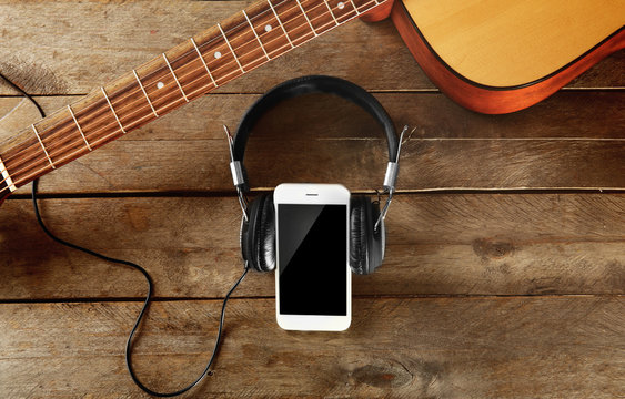 Smartphone with headphones on wooden background
