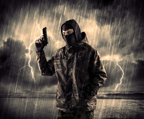 Dangerous armed terrorist with mask and gun in a thunderstorm wi