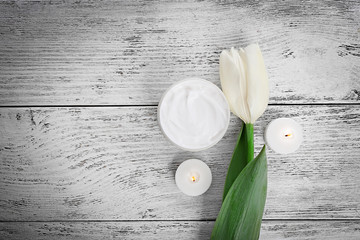 Cosmetic cream with tulip on white wooden background