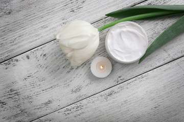 Cosmetic cream with tulip on white wooden background