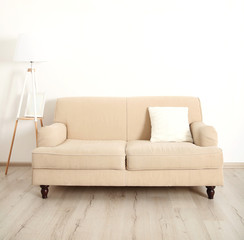 Beige couch and lamp on white wall background