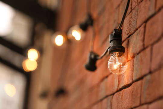 Lamp garland on brick wall background, closeup