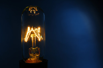 Illuminated light bulb on dark blue background