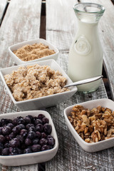 Old barn wood table with oatmeal with chia seeds, brown sugar, blueberries, walnuts, and an antique milk bottle