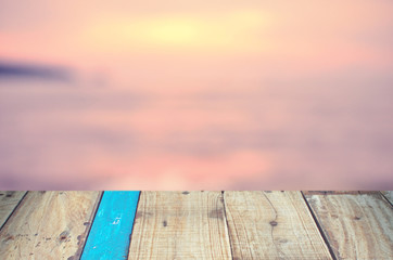 Naklejka na ściany i meble Blur tropical sunset beach with old empty wood table background.