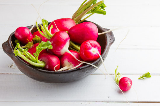 Red radish in clay bowl on white background