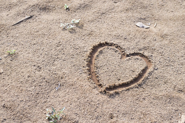 Fototapeta na wymiar heart on sand draw wtih finger
