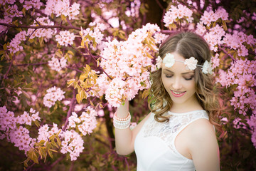 Spring / pretty woman with flower hair band in front of a blossoming apple tree