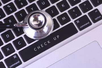 close up of stethoscope and CHECK UP written on laptop keyboard