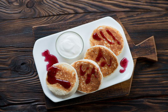 Plate with curd pancakes in a rustic wooden setting, top view