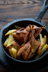 Close-up of a cast-iron frying pan with whole baked quails