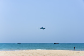 Fototapeta na wymiar Plane is landing over the beach