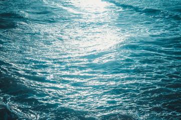 Blue waves of the sea and foam background, reflections of sun light