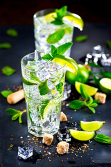 Mojito cocktail on a table. Summer cocktail with rum, lime, mint, ice cubes and brown sugar