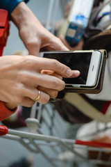 Mother and child on shopping trip. Closeup on young woman with mobile phone and store cart 