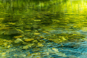 Rippling water with sunbeam and stones in the water
