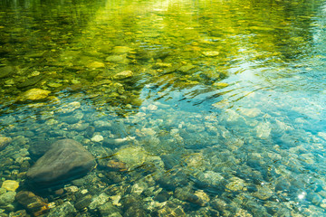 Rippling water with sunbeam and stones in the water