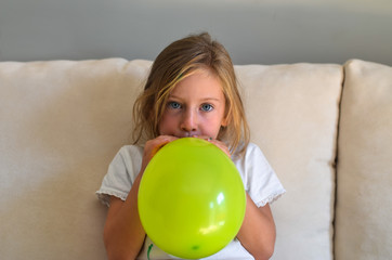 Fototapeta na wymiar Girl inflating a balloon