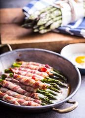 Asparagus. Asparagus and roll bacon. Grilled asparagus with rolled bacon and fried egg. Fried old pan full of rolled bacon with green asparagus and fried egg.