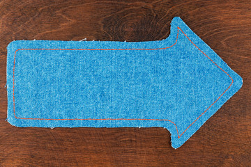 Arrow made of jeans lies on a wooden background