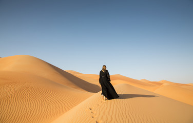 A woman in abaya in sanddunes in Liwa Desert, Aby Dhabi, UAE