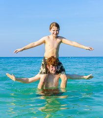 brothers enjoying the clear warm water and play piggyback