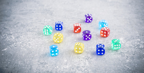 Dice in a variety of colors on stone table, symbol of chance and luck. Concept of diversity, leisure game or numbers.