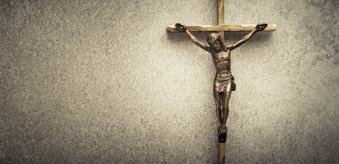 Crucifix of Jesus on the cross with stone background. Symbol of christian religion and belief. Image composed with copy space.