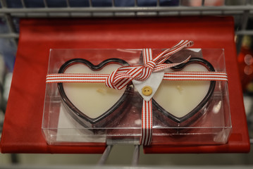 Two Valentines red heart candles in background of decorating store interior 