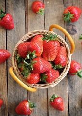 Fresh organic strawberries in a basket on a wooden table.