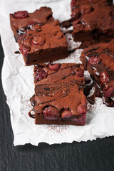 Homemade chocolate sweet brownies cakes with cherry and chocolate sauce or syrup on a dark background, closeup