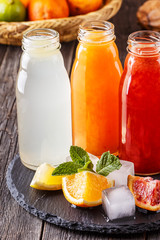 Fresh citrus juices on a dark wooden background.