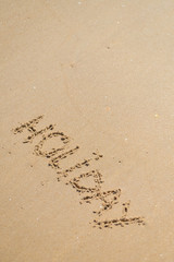 Fototapeta premium Top view on inscription Holiday on sea sand beach with the sun rays against wave foam. vacation concept