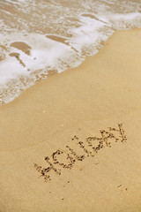 Top view on inscription Holiday on sea sand beach with the sun rays against wave foam. vacation concept
