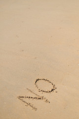 Fototapeta na wymiar NO sign written in sand on beach texture sunny background. 